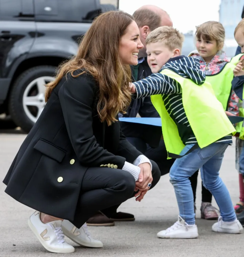 kate middleton wearing Veja sneakers with black fabric upper and white sole, featuring Veja's signature 'V' logo and made with eco-friendly materials.