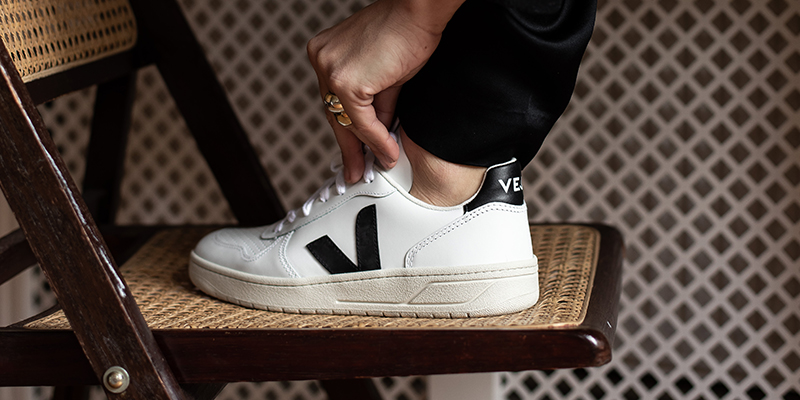 Photo of Veja sneakers made from sustainable materials, featuring white organic cotton uppers, wild rubber soles sourced from the Amazon rainforest, and the signature V-logo on the side.