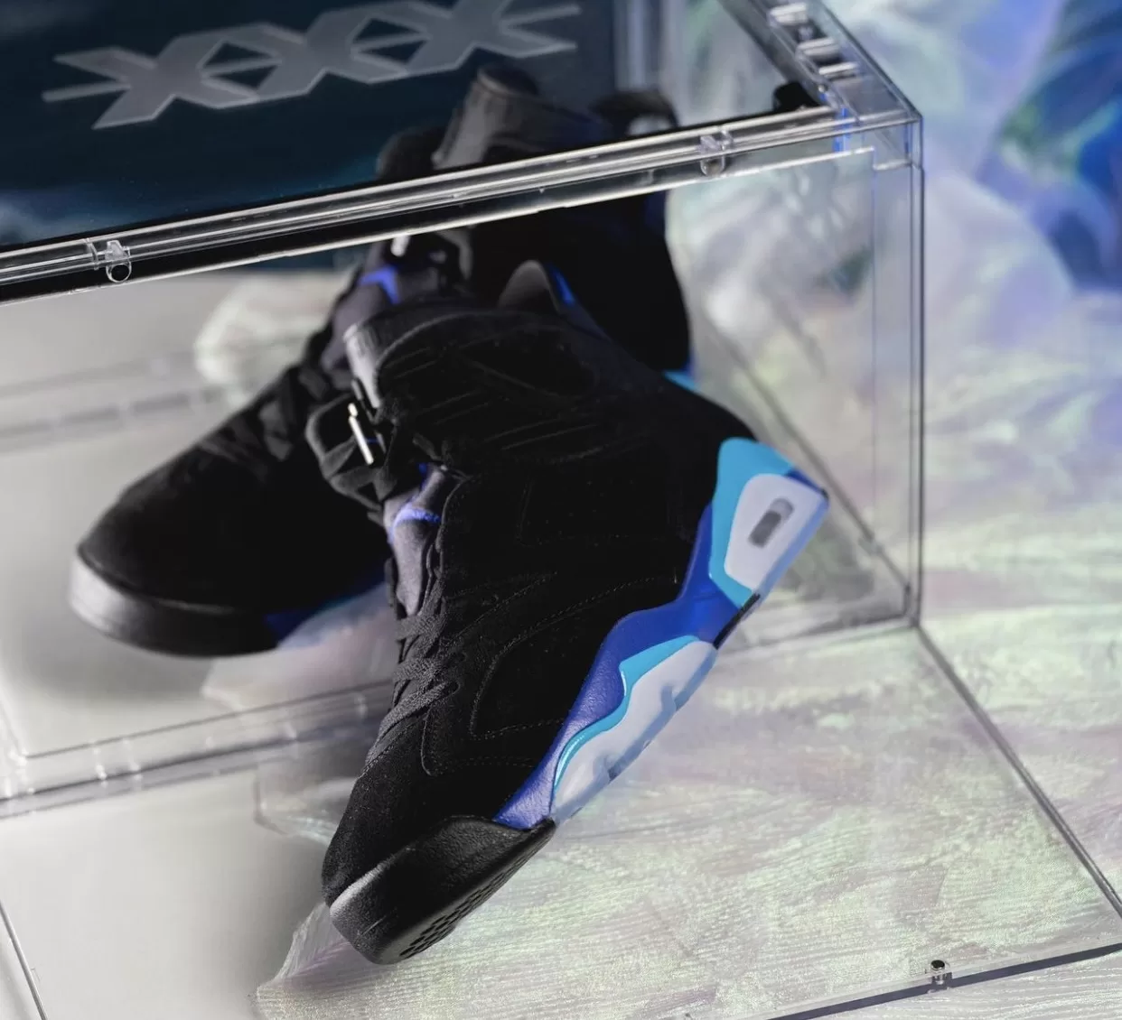 Image displaying the Air Jordan 6 "Aqua" sneakers in a Black, Bright Concord, and Aquatone color scheme, featuring a sleek design with a Black nubuck upper and contrasting accents, resting on an icy translucent outsole.