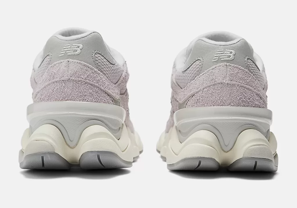 Image showcasing the New Balance 9060 sneakers in the "December Sky" colorway. Muted pink and gray hues with off-white and concrete accents, featuring a shaggy suede overlay and a distinctive diamond-shaped outsole pattern.