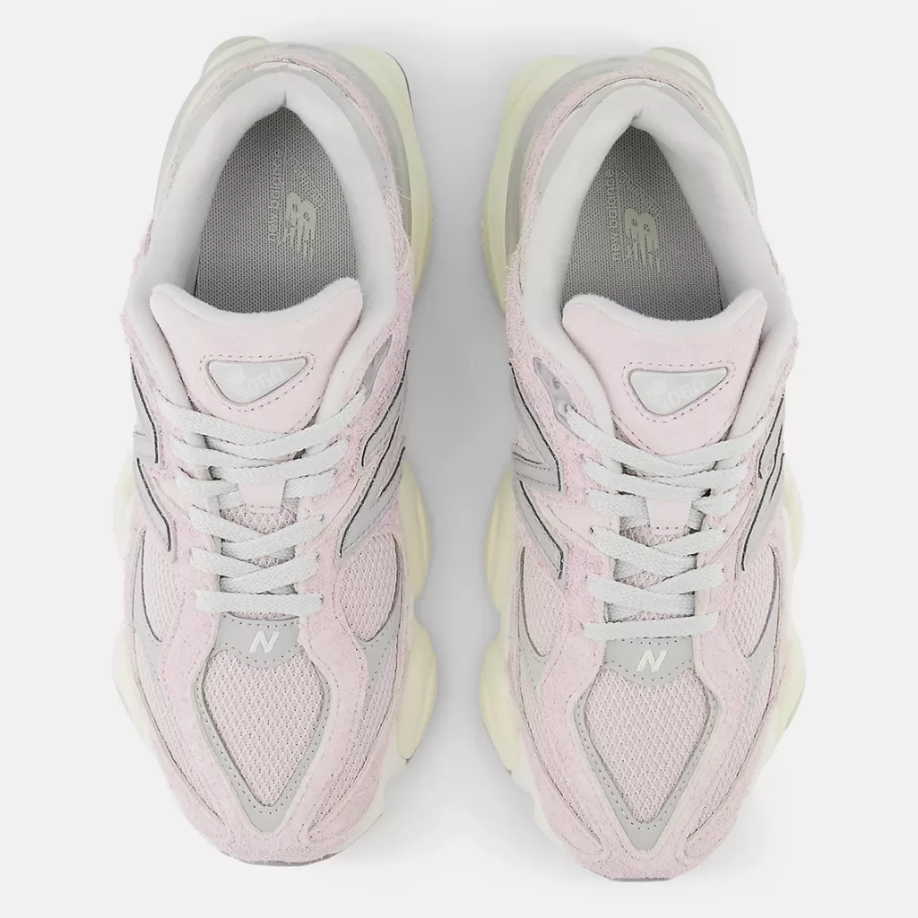 Image showcasing the New Balance 9060 sneakers in the "December Sky" colorway. Muted pink and gray hues with off-white and concrete accents, featuring a shaggy suede overlay and a distinctive diamond-shaped outsole pattern.