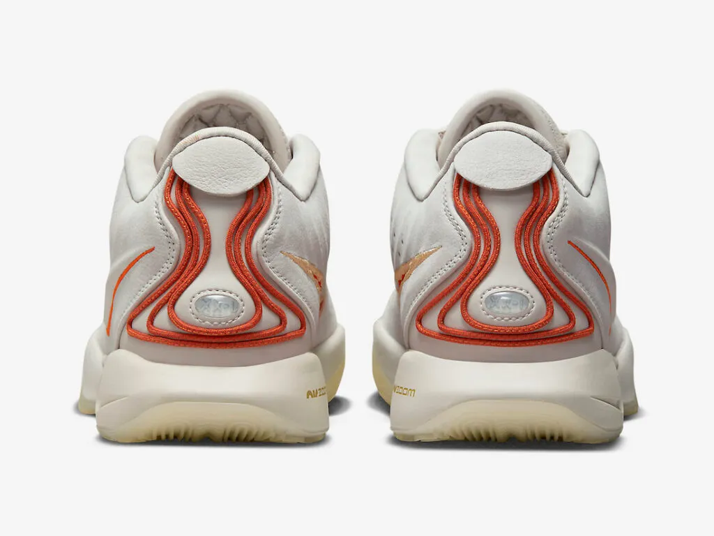 Back: A pair of Nike LeBron 21 basketball sneakers in the "Akoya" colorway. The shoes feature a semi-translucent white rubber sole with a clean white midsole. The uppers are constructed from off-white leather with vibrant orange accents. The Nike Swoosh is lined in orange, and the laces feature orange lace locks and an orange dubrae. LeBron's logo can be found on the tongue, once again in orange. The heels feature an orange pattern design, with XXI symbolizing 21.