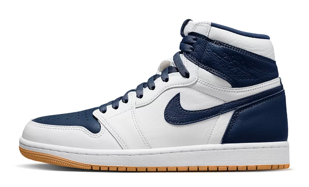 A close-up photo of the Air Jordan 1 High "Summit White Obsidian" sneaker. The sneaker has a predominantly white leather upper with obsidian blue accents on the Swoosh, Wings logo, collar, and tongue label. The Nike Air logo is embroidered on the tongue and heel in black. The midsole is white and the outsole is gum rubber.
