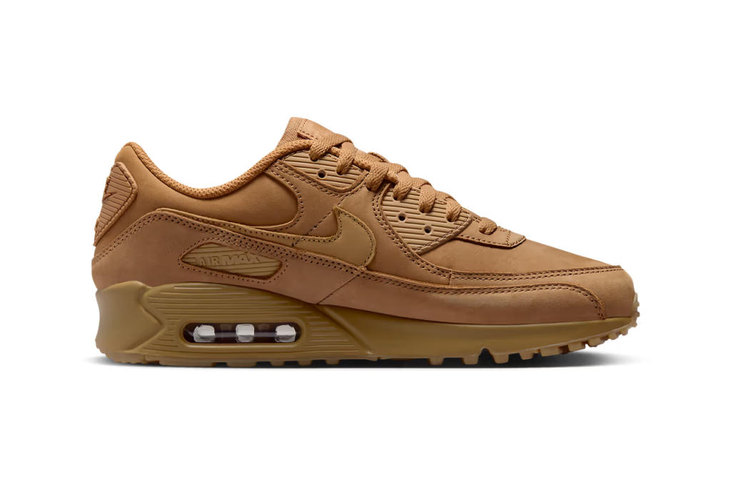 A pair of Nike Air Max 90 sneakers in "Wheat" colorway. The shoes feature a suede and nubuck upper with matching Swooshes, laces, and branding elements. The sole unit is also brown, with a visible Air unit and semi-translucent outsole.