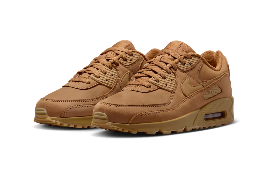 A pair of Nike Air Max 90 sneakers in "Wheat" colorway. The shoes feature a suede and nubuck upper with matching Swooshes, laces, and branding elements. The sole unit is also brown, with a visible Air unit and semi-translucent outsole.
