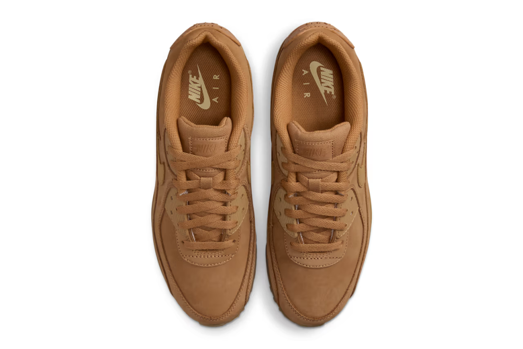 A pair of Nike Air Max 90 sneakers in "Wheat" colorway. The shoes feature a suede and nubuck upper with matching Swooshes, laces, and branding elements. The sole unit is also brown, with a visible Air unit and semi-translucent outsole.