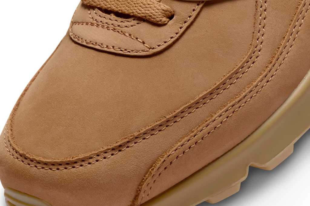 A pair of Nike Air Max 90 sneakers in "Wheat" colorway. The shoes feature a suede and nubuck upper with matching Swooshes, laces, and branding elements. The sole unit is also brown, with a visible Air unit and semi-translucent outsole.