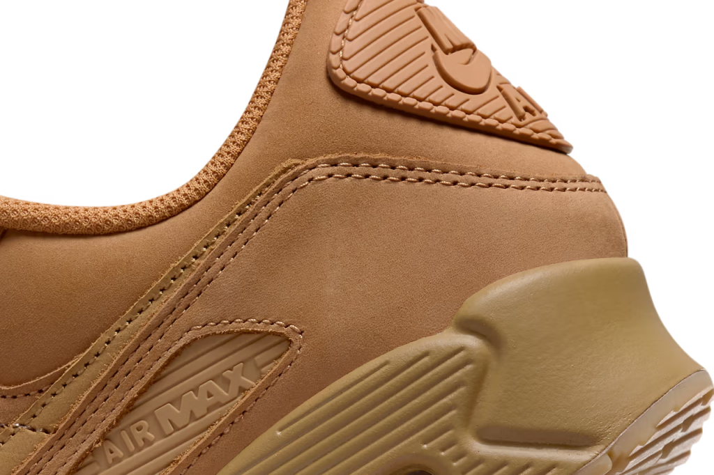 A pair of Nike Air Max 90 sneakers in "Wheat" colorway. The shoes feature a suede and nubuck upper with matching Swooshes, laces, and branding elements. The sole unit is also brown, with a visible Air unit and semi-translucent outsole.