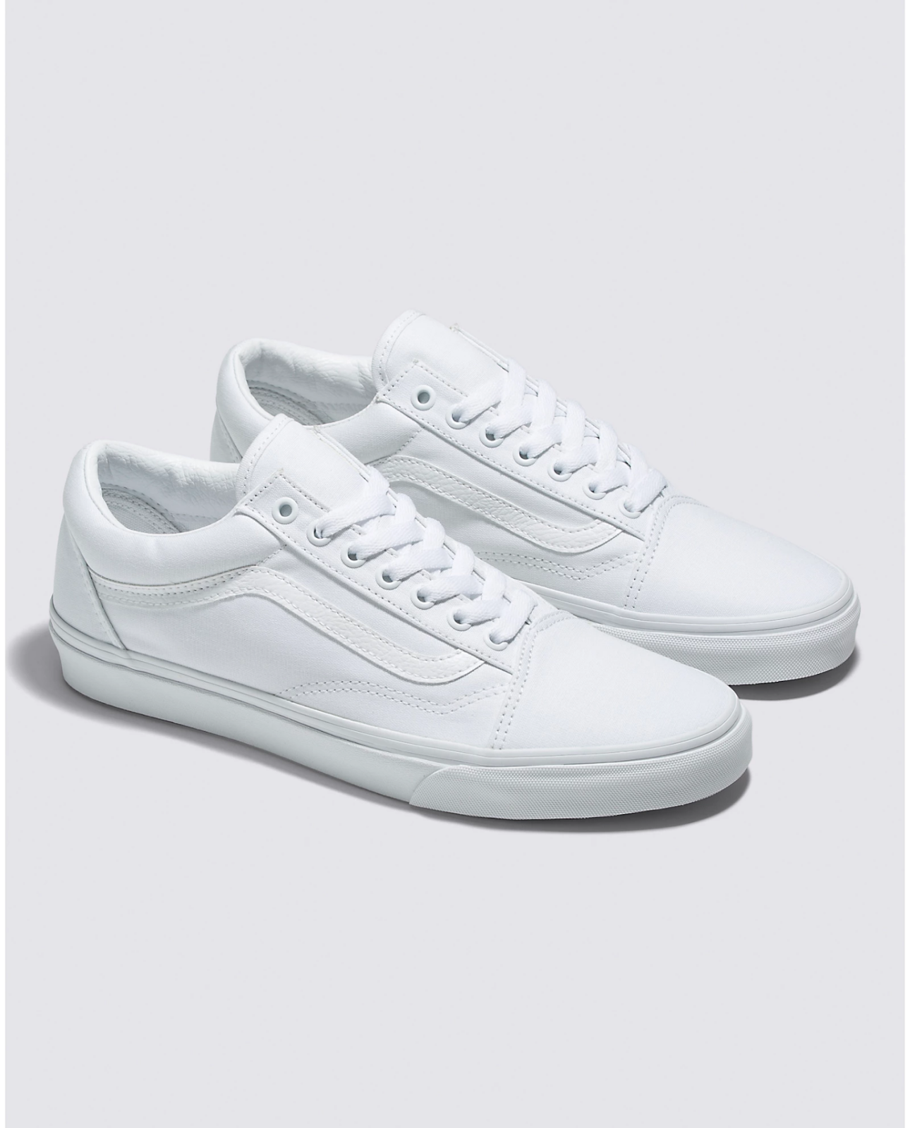 General: White canvas Vans sneakers.
Specific model: White Vans Old Skool sneakers.
Action: A person wearing white Vans sneakers.
Style: Classic white sneakers for a casual look.
Brand: White Vans, a popular brand of casual sneakers.